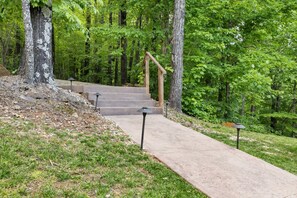 A concrete pathway leading to a wooden staircase surrounded by lush greenery. - Mountain Crest Cabin-Relaxing Vacation in Jasper (Jasper)