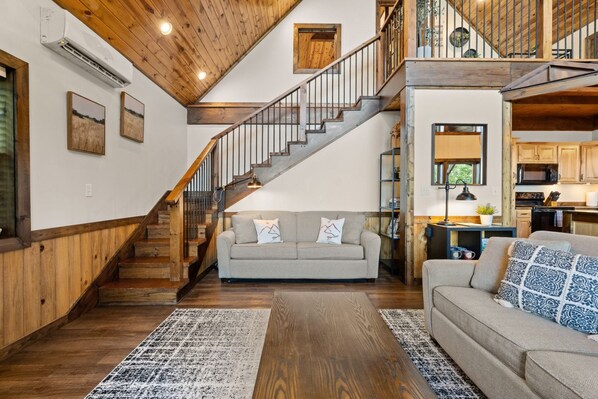 A spacious living area with a wooden staircase, a sofa, and a kitchen area. - Mountain Crest Cabin-Relaxing Vacation in Jasper (Jasper)