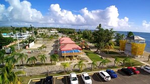 Un hôtel situé sur la côte, avec un bâtiment à toit rouge, un parking où sont garées plusieurs voitures et une vue sur l’océan.