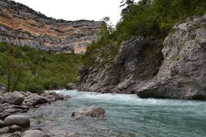 Um rio serpenteando por uma paisagem rochosa com penhascos e vegetação.
