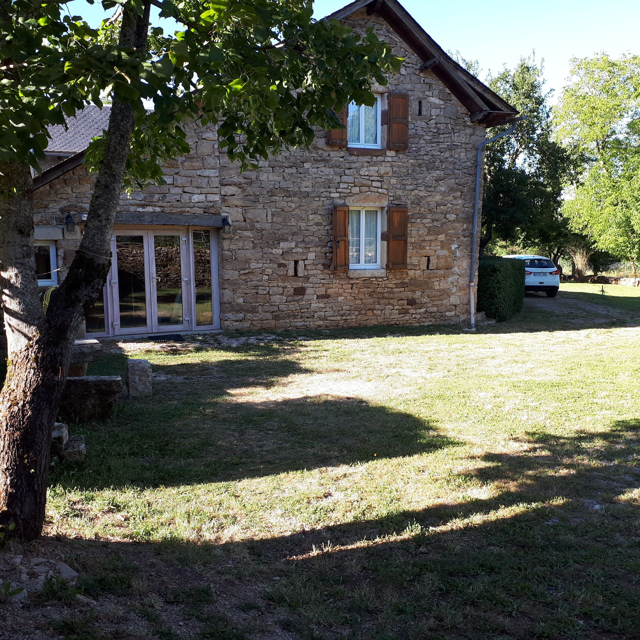 A stone house with a sloped roof, a small window with shutters, and a door with glass panels.