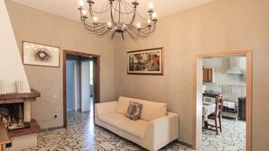 A living room with a beige sofa, a chandelier, and a patterned floor. - Spacious Apartment in the Heart of Tuscany (Badia A Cerreto)