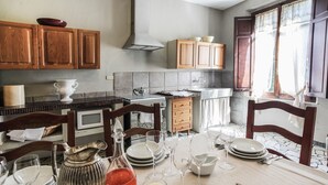 A well-lit kitchen with wooden cabinets, a stove, and a dining area set for a meal. - Spacious Apartment in the Heart of Tuscany (Badia A Cerreto)