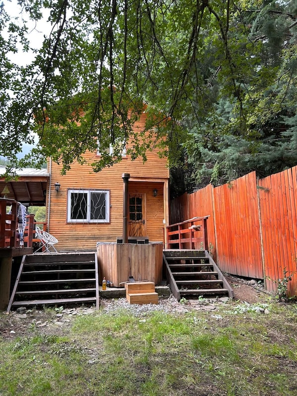 A wooden cabin with a wooden deck and a red fence.