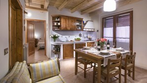 Una cucina accogliente con mobili in legno, un tavolo da pranzo per quattro persone e un divano a righe.