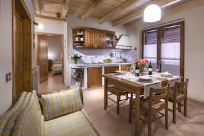 Une cuisine chaleureuse avec des meubles en bois, une table à manger dressée pour quatre personnes et un canapé à rayures.