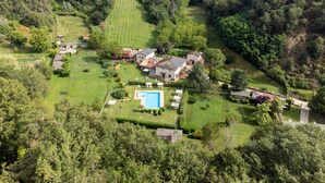 Vista aerea di una grande tenuta con diversi edifici, una piscina e ampi prati verdi.