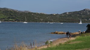 A coastal scene with boats on the water, a beach, and hills in the background. - Seafront house with garden (Cannigione)