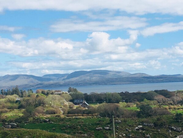 A rural landscape with a lake, mountains, and scattered houses.