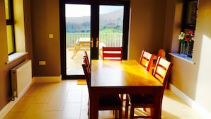 Un comedor con una mesa y sillas, una vista de una terraza con mesa y sillas, y una ventana con un florero.