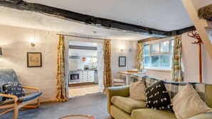 A cozy living room with a sofa, a chair, a small table, and a kitchen in the background. - 1 bedroom accommodation in Shap, near Penrith (Shap, near Penrith)