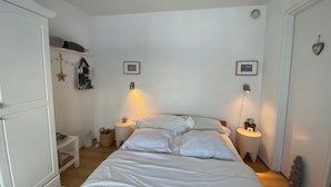 Een slaapkamer met een bed, nachtkastjes, een kledingkast en wandlampen.