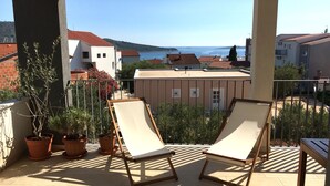 Un balcone con due poltrone, piante in vaso e vista sul mare e sugli edifici.