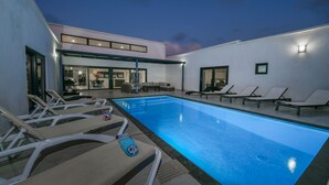 Ein moderner Poolbereich im Freien mit Liegestühlen und Essbereich.