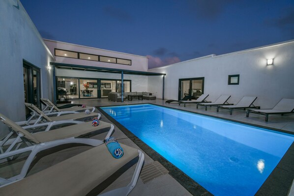 Un área de piscina moderna al aire libre con sillones de descanso y zona de comedor.