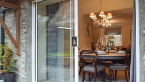 Un coin repas avec une table dressée pour quatre personnes, un lustre et un mur en pierre.