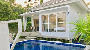 Ein modernes Haus mit Swimmingpool, überdachter Terrasse und einer Treppe, die zu der oberen Etage führt.