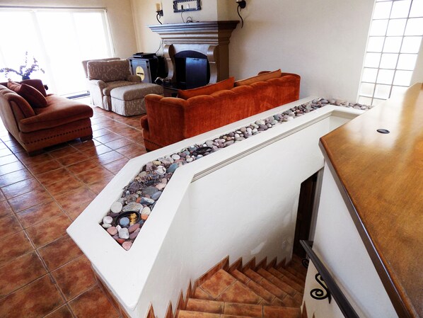 A living room with a fireplace, a staircase, and a seating area with a sofa and armchairs.