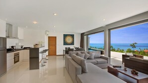A modern kitchen with a dining area and a large window overlooking the ocean.