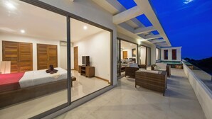A modern bedroom with a large sliding glass door leading to a balcony with outdoor seating.