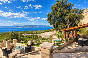 A terrace with outdoor furniture, a pool, and a view of the sea and hills. - Villa with heated Swimmingpool, barbecue , terrace with sea view, up to 6 people (Baska Voda)