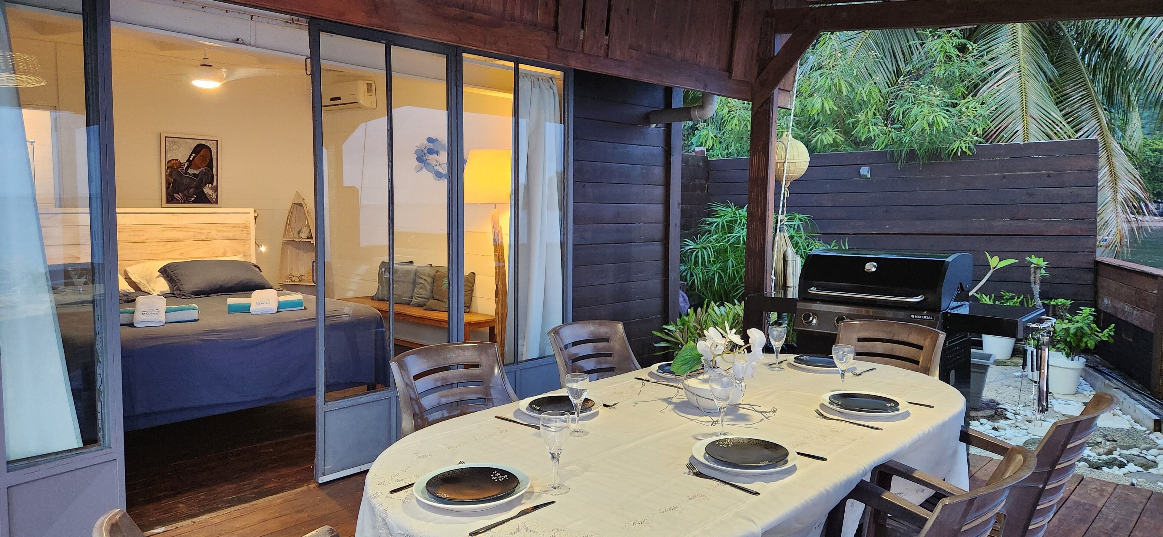 An outdoor dining area with a table set for four, surrounded by wooden chairs.