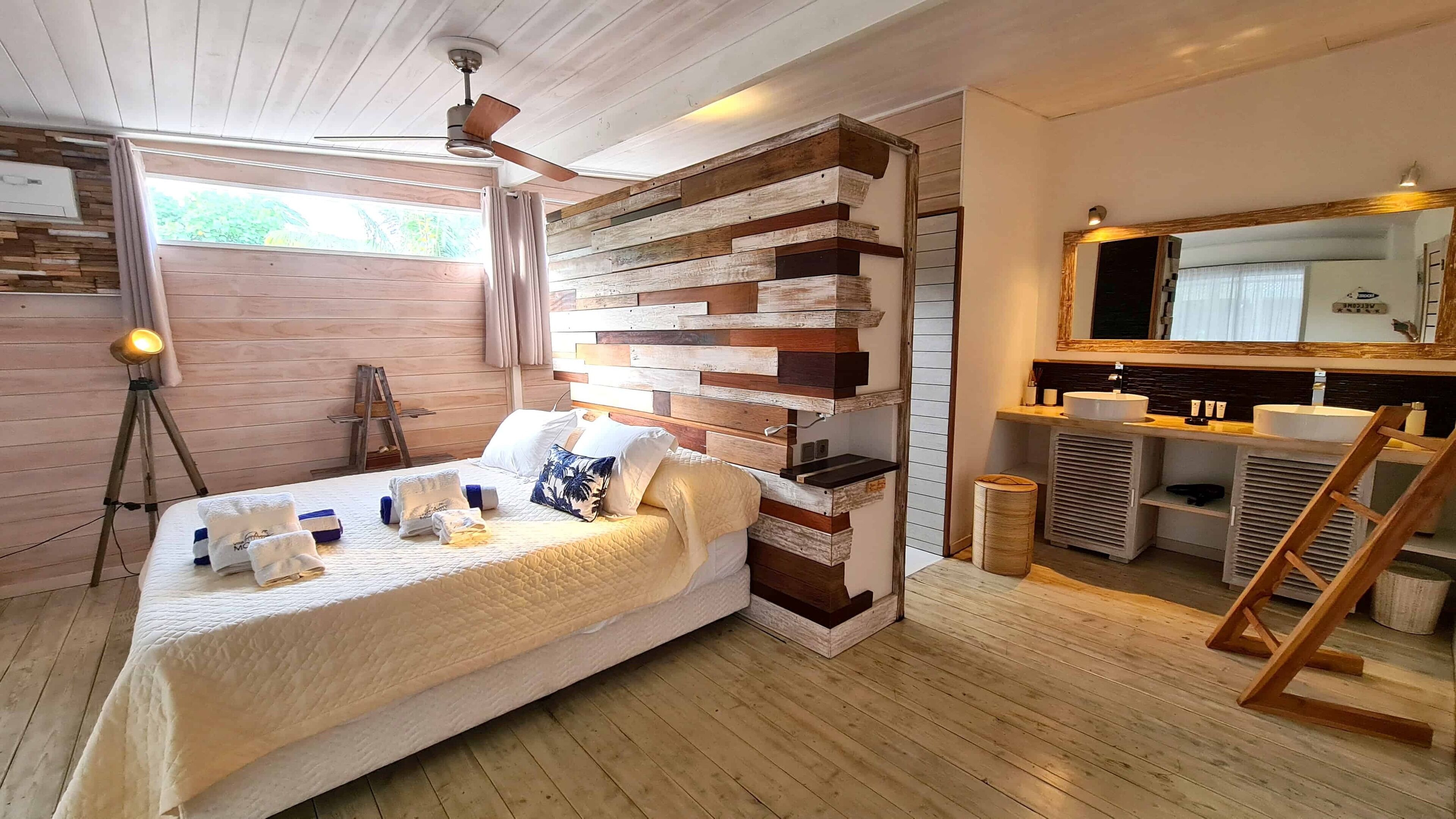 Une chambre à coucher avec une tête de lit en bois, un lit avec une literie blanche, une lampe de chevet et un plancher en bois.