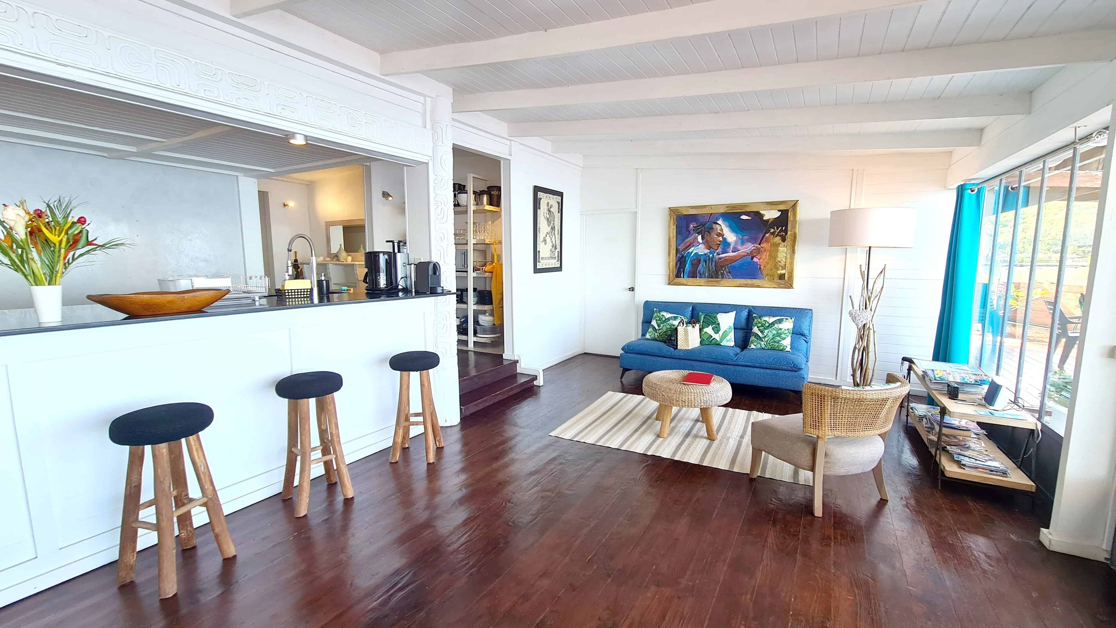 A modern kitchen with a bar area, a blue sofa, and a dining area with a table and chairs.
