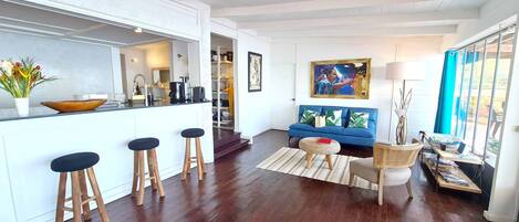 A modern kitchen with a bar area, a blue sofa, and a dining area with a table and chairs.