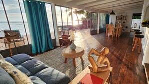 Een ruime woonkamer met uitzicht op de oceaan, houten vloeren, een eethoek en een gezellige zithoek.