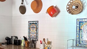 A kitchen with white tiled walls, wooden cabinets, and a granite countertop.