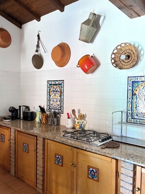 A kitchen with white tiled walls, wooden cabinets, and a granite countertop.