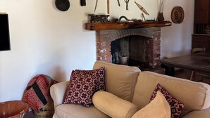 A cozy living room with a beige sofa, patterned cushions, and a fireplace. - Castiadas, typical Sardinian private villa with swimming pool and garden (Castiadas)