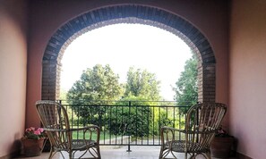 A patio with two wicker chairs and a table, an archway, and a view of greenery. - Castiadas, typical Sardinian private villa with swimming pool and garden (Castiadas)