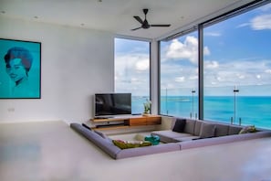 Relax in this ocean-view living room with a large flat-screen TV and comfortable seating area.