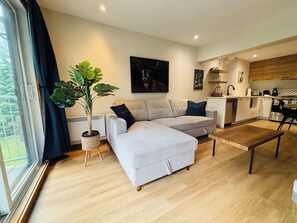 Un salon moderne avec un canapé d’angle gris, une table basse et une plante en pot.