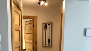 Un corridoio con porte in legno, un quadro con pagaie e una lampada a soffitto.
