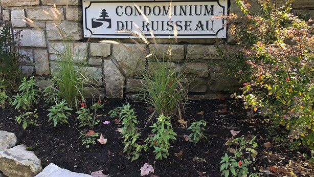 Un muro in pietra con un cartello che riporta la scritta "CONDOMINIUM DU RUSSEAU".