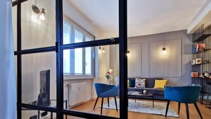 Una sala de estar moderna con un sofá, dos sillones, una mesa de centro y una estantería.