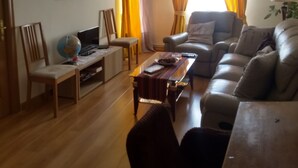 Uma sala de estar com piso de madeira, um sofá, uma mesa de centro, uma televisão e um globo.