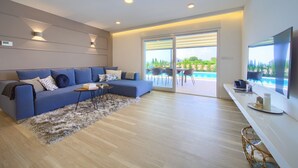 A modern living room with a blue sofa, a coffee table, and a TV on a stand. - Villa Elegant with heated pool (Kvarner - Vrh) (Vrh)