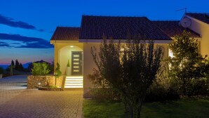 A house with a tiled roof, a well-lit entrance, and a paved driveway. - Villa Elegant with heated pool (Kvarner - Vrh) (Vrh)