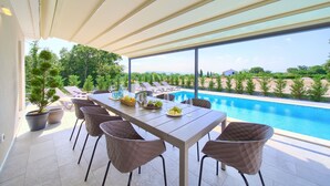 A terrace with a pool, dining table, chairs, and potted plants. - Villa Elegant with heated pool (Kvarner - Vrh) (Vrh)