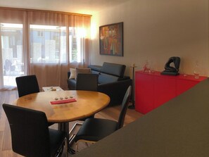 A dining area with a round table, black chairs, a red cabinet, and a painting on the wall. - Seelenmattli Appartement/Fewo 4-Bettwohnung by Interhome (Engelberg)