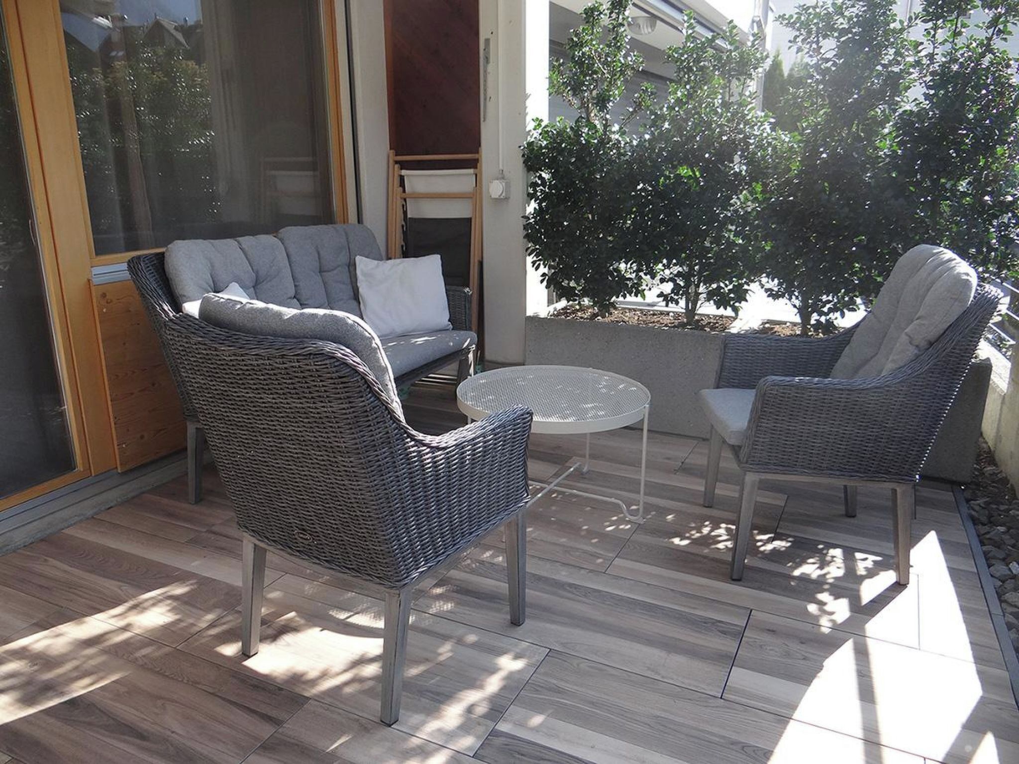 An outdoor seating area with wicker furniture and a glass door leading to a patio.