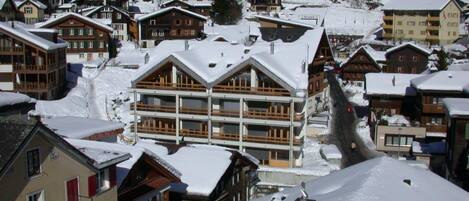 A snow-covered mountain village with traditional chalet-style buildings.