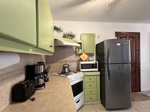 Compact kitchen with a refrigerator, microwave, gas stove, and oven, perfect for everyday meals.