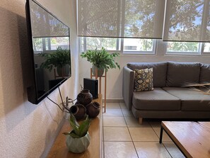 Relax in this stylish living room with a flat-screen TV, comfortable sofa, and potted plants.