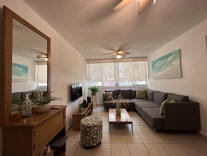 Relax in a spacious living room with a large mirror, flat-screen TV, and comfortable seating area.