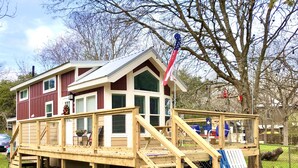 Une maison à deux étages avec une terrasse en bois et un drapeau.